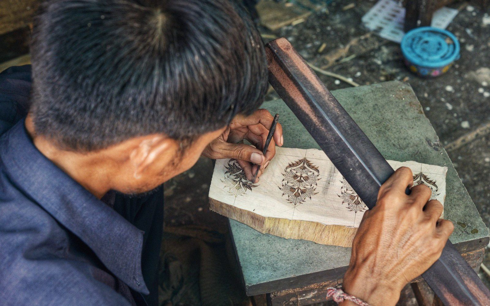 Hands laying a carved block onto cloth at a printing table