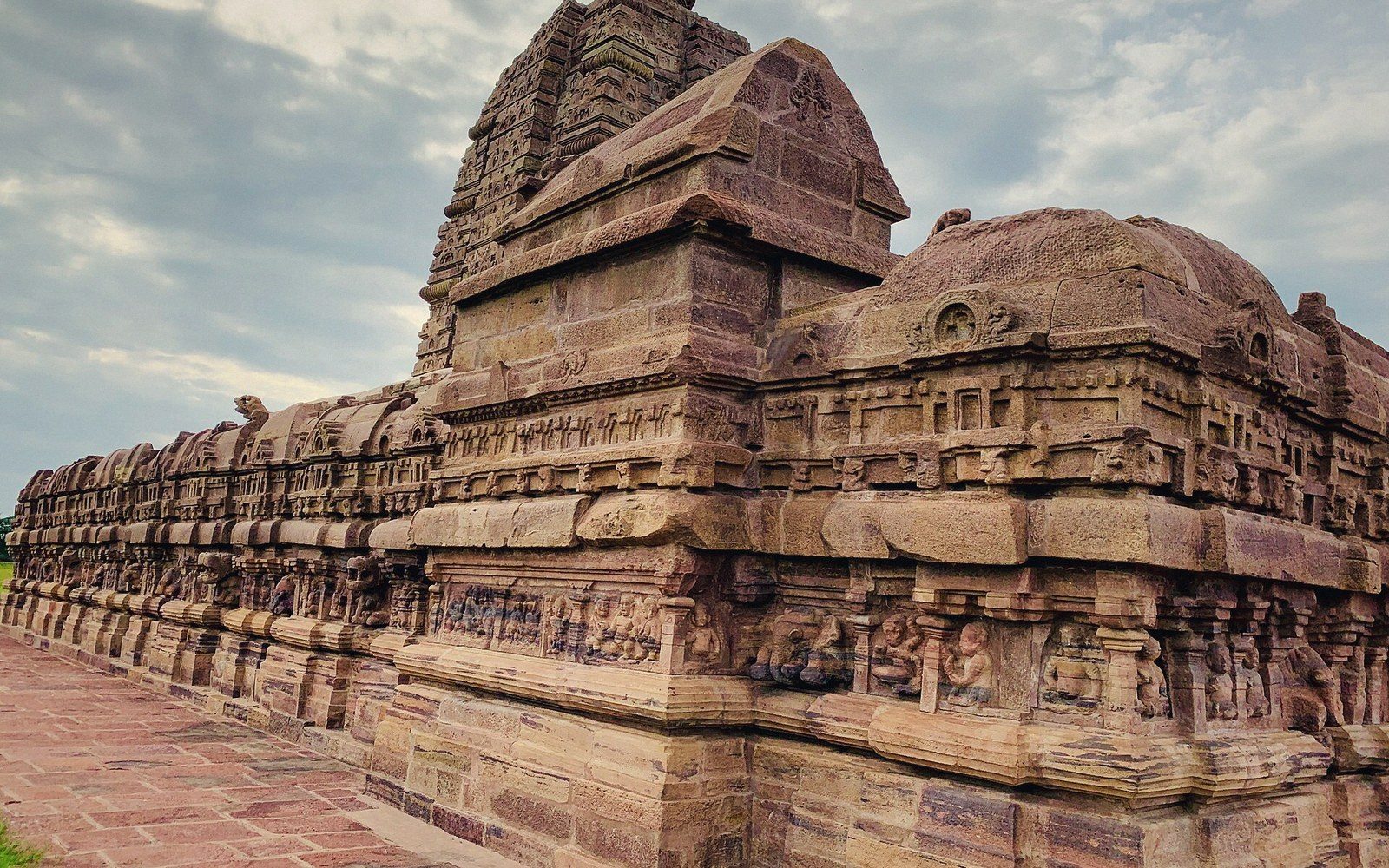 Stone temple wall with intricate carved panels and a curved tower rising above