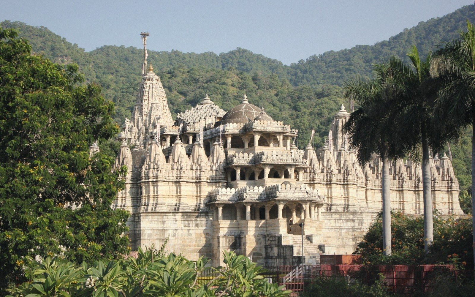 Marble Jain temple with carved spires and domes surrounded by forested hills