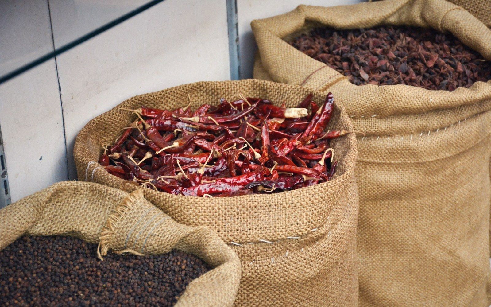 Burlap sacks filled with dried red chilies, star anise, and black peppercorns