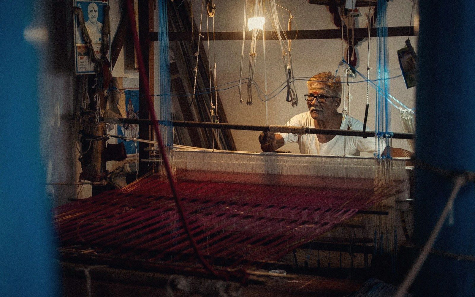 A loom in a workshop with a weaver at it